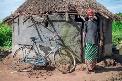 Woman stands next to bicycle she financed through a social enterprise in Uganda