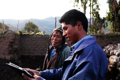 A microfinance agent equipped with a tablet speaks with a customer in the Peruvian highlands. 