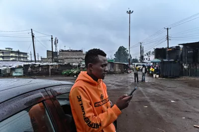 A ride-hailing driver checks his app beside his car in Nairobi, Kenya.