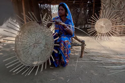 A woman in India weaves a basket