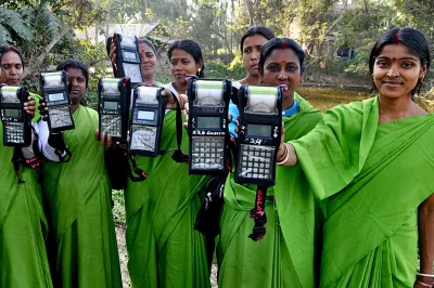 Women agents of a microcredit institution in India show the devices they use for collections.