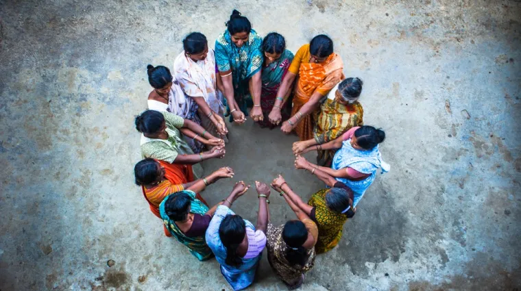 a group of women standing in a circle with their hands together in the center