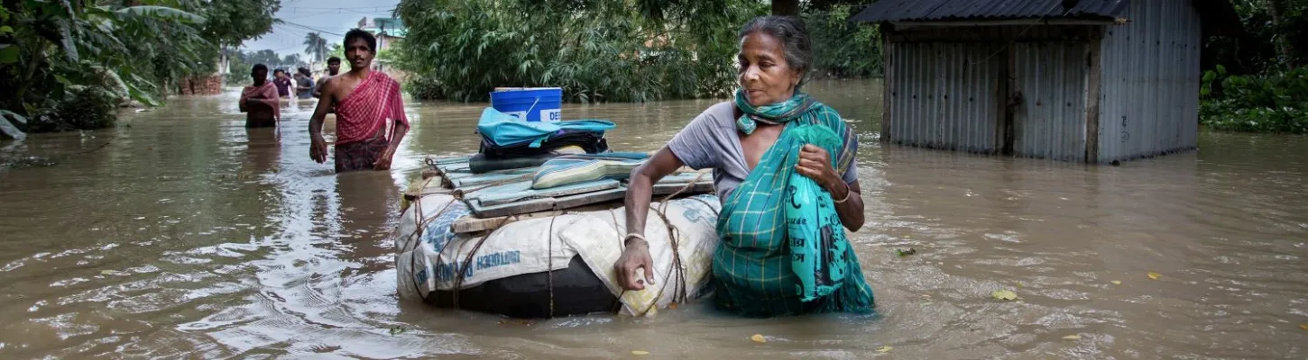 a woman pulling her floating belongings behind her on a flooded road