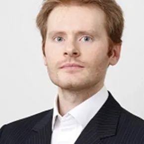 headshot of man in dark suit against white background