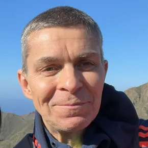 headshot of man against blue background