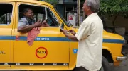 A man pays a taxi driver using his mobile phone in India.