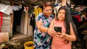 Two women are checking a mobile phone to obtain the payment authorisation code