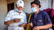 Two men look at a phone. Photo credit: CGAP Photo (Lorena Velasco via Communication for Development Ltd)