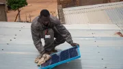 A man installs off-grid solar panels on top of a building