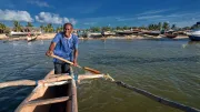 A man rows a boat near shore