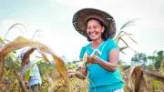 A woman smiles as she works in a field in the Philippines