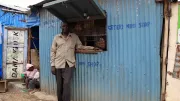 Man stands outside small shop, Kenya.