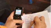 Person with mobile phone writing a list.