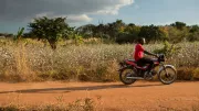 Farmer motorcycles down dirt road in rural Mozambique