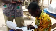 Man writes down a record of a financial transaction, Ghana.