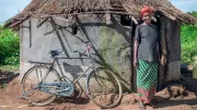 Woman stands next to bicycle she financed through a social enterprise in Uganda