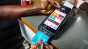 A digital finance agent helps a customer swipe card at point-of-sale device in Lagos, Nigeria.