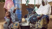 Women use a machine to process black-eyed peas