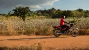 A man rides his motorcycle down an open road in rural Mozambique.
