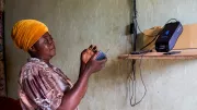 A pay-as-you-go (PAYGo) solar customer in Nigeria uses a radio powered by solar energy. 