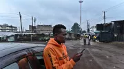 A ride-hailing driver checks his app beside his car in Nairobi, Kenya.