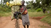 Woman uses bicycle to take produce to market in Uganda