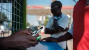Teller holds smartphone in Zambia. Photo: Nyani Quarmyne, IFC